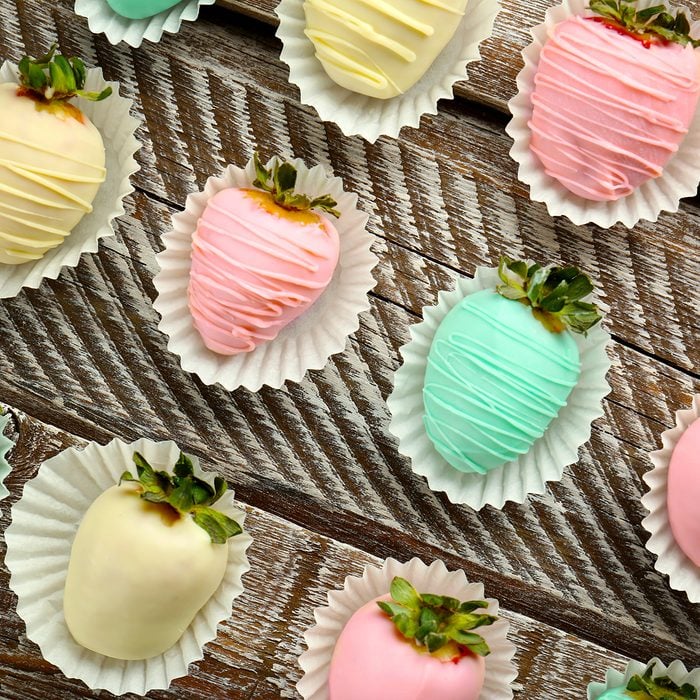 Strawberries covered with colorful chocolate icing on wooden background