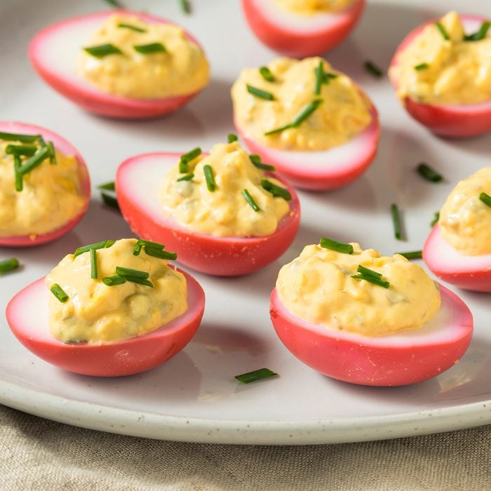 Homemade Pink Pickled Deviled Eggs with Chives;