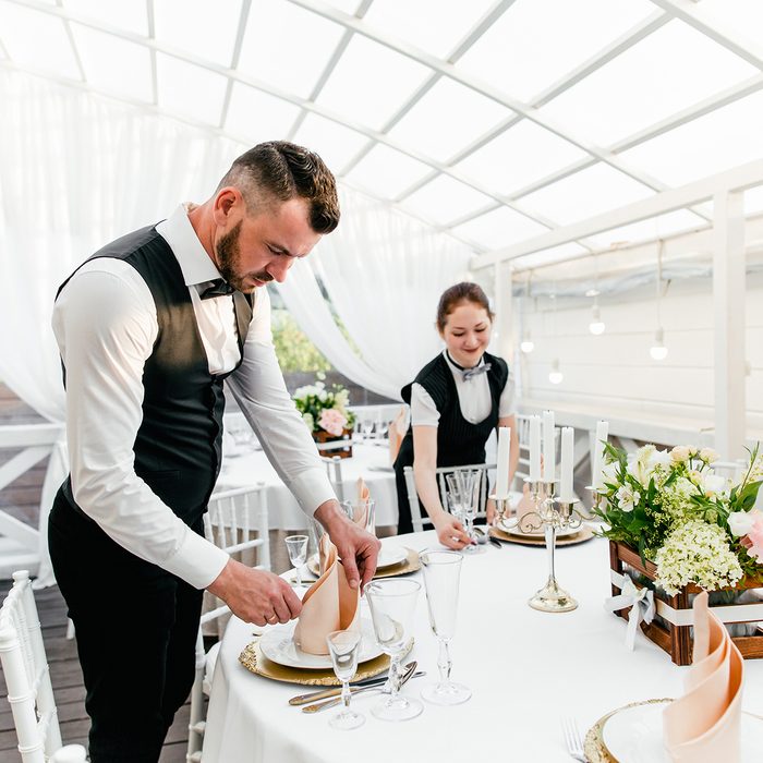 Two male and female waiters serve a table in the restaurant wiping glasses for wine; Shutterstock ID 1145179853; Job (TFH, TOH, RD, BNB, CWM, CM): Taste of Home