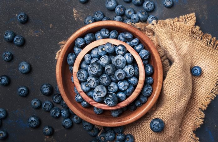 Fresh blueberries in wooden bowl on dark kitchen table background, copy space, top view