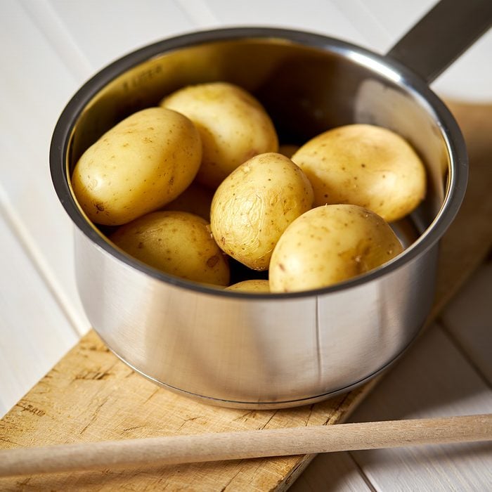 Young potatoes boiled in pot on wooden board on white wooden table; Shutterstock ID 1398365882; Job (TFH, TOH, RD, BNB, CWM, CM): TOH
