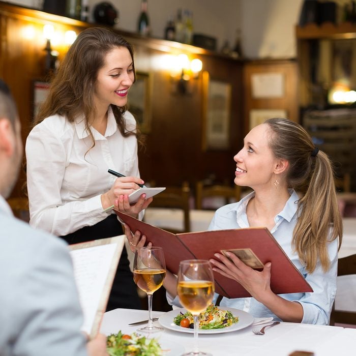 Smiling waitress offering to young couple tasty dishes. Focus on girl ; Shutterstock ID 746909929; Job (TFH, TOH, RD, BNB, CWM, CM): Taste of Home