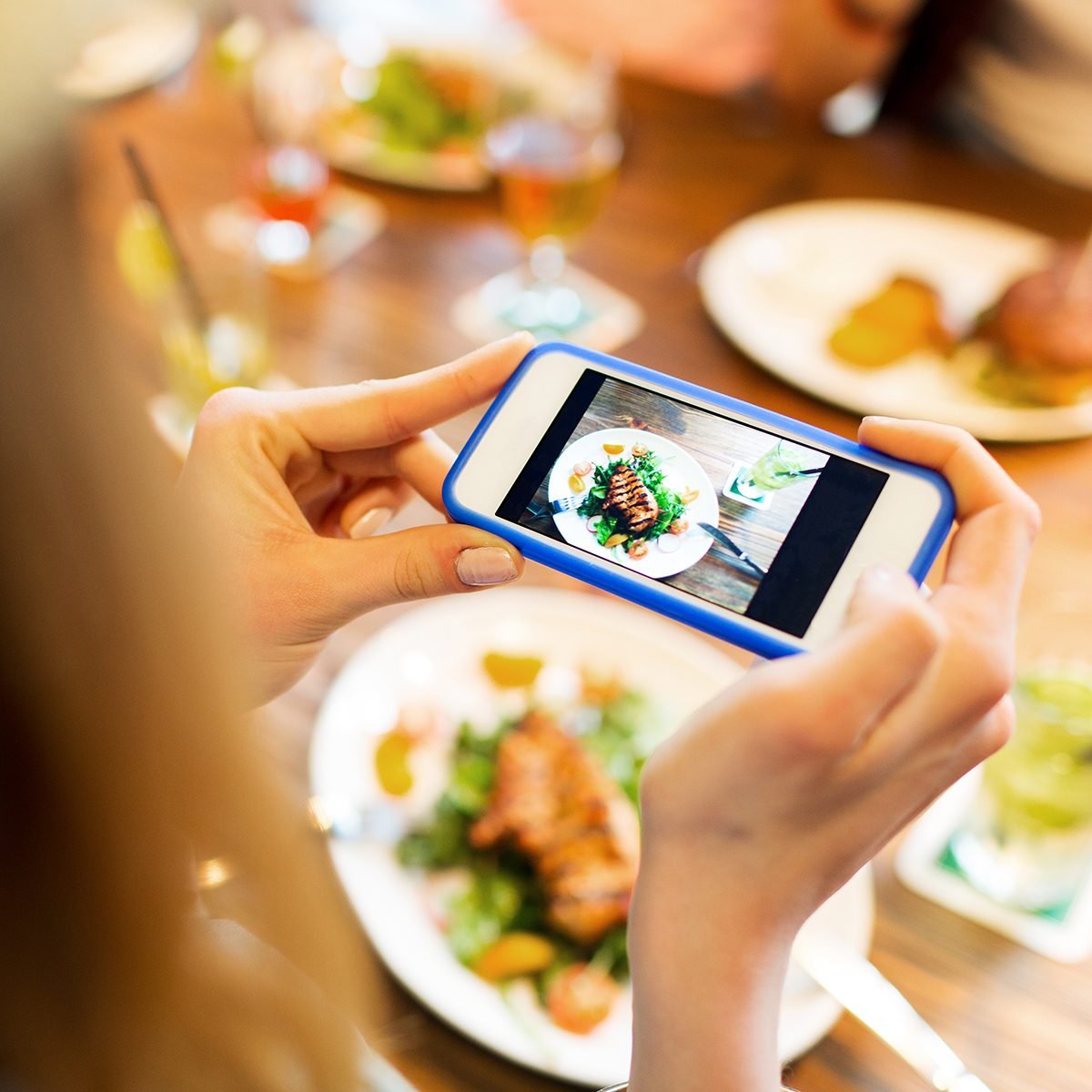 woman photographing food by smartphone