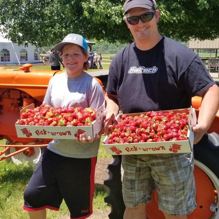 Adult and child holding trays of strawberries