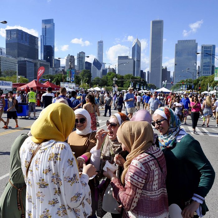 Taste of Chicago muslim women eating street foot with chicago skyline in background