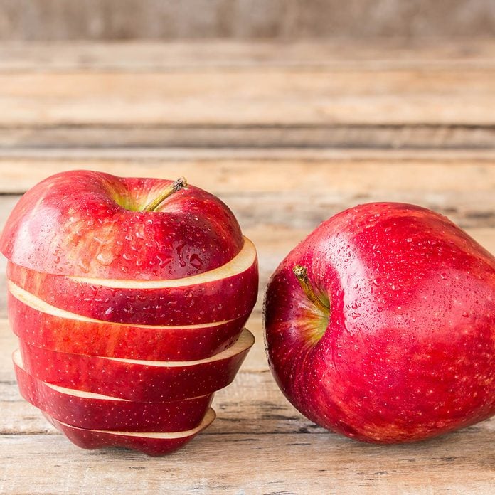 Close up of a sliced red apple on a wooden table.