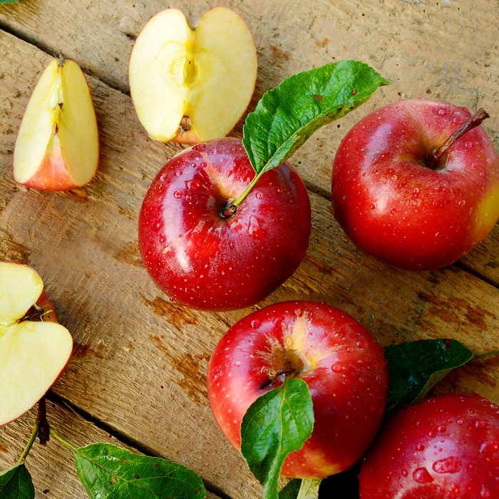 Red apples or Gala apples with fresh leaf and water drop on wooden background.