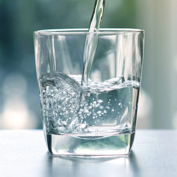 Close up pouring purified fresh drink water from the bottle on table in living room