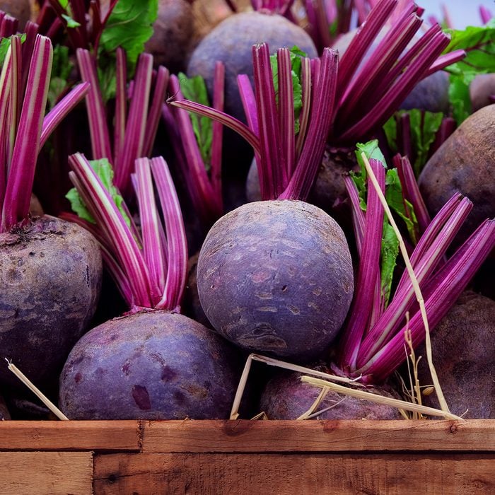 Fresh harvested beetroots in wooden crate, beets with leaves in the market