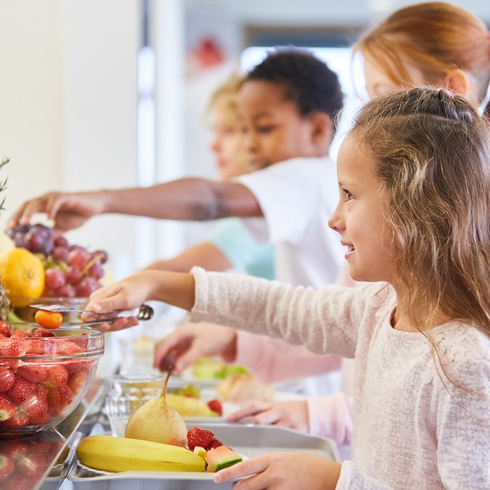 Girl and other kids at the fruit buffet at the cafeteria in elementary school