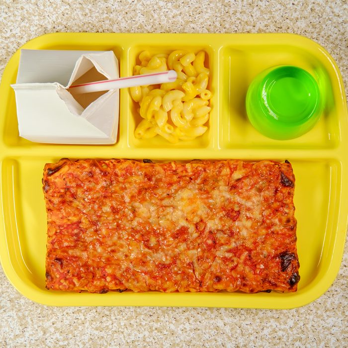 Grade school lunch tray with pizza with small carton of milk mac-n-cheese and green gelatin for dessert