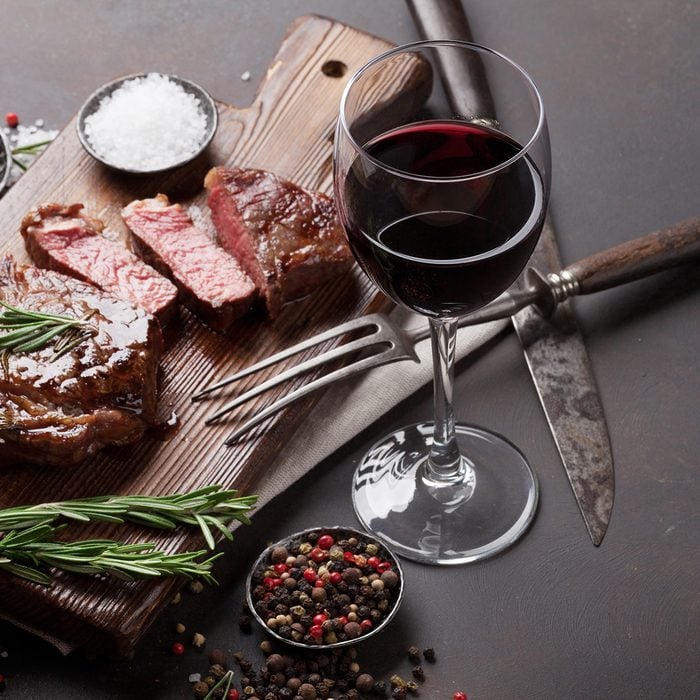 Grilled ribeye beef steak with red wine, herbs and spices on stone table