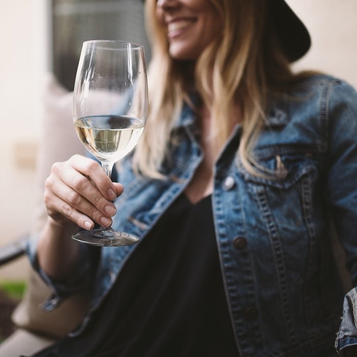 happy blonde woman enjoying white wine and smiling