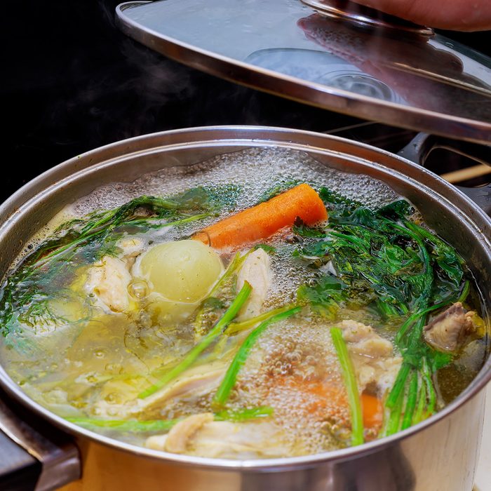 Ingredients for preparing chicken bone broth in a pot chicken, onions, celery root, carrots, parsley