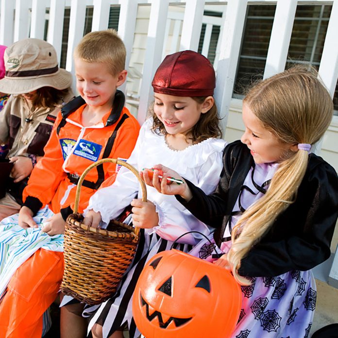 Halloween: Kids Sit On Porch And Look At Halloween Candy