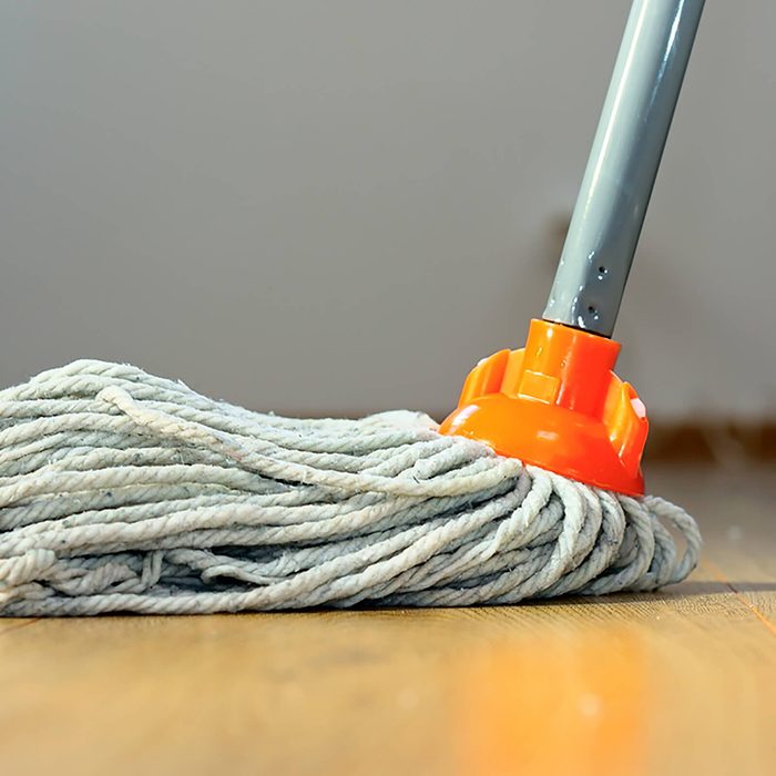cleaning wooden floor with orange wet mop