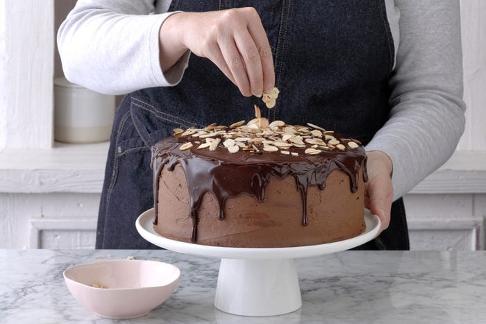 Topping chocolate ganache cake with almonds