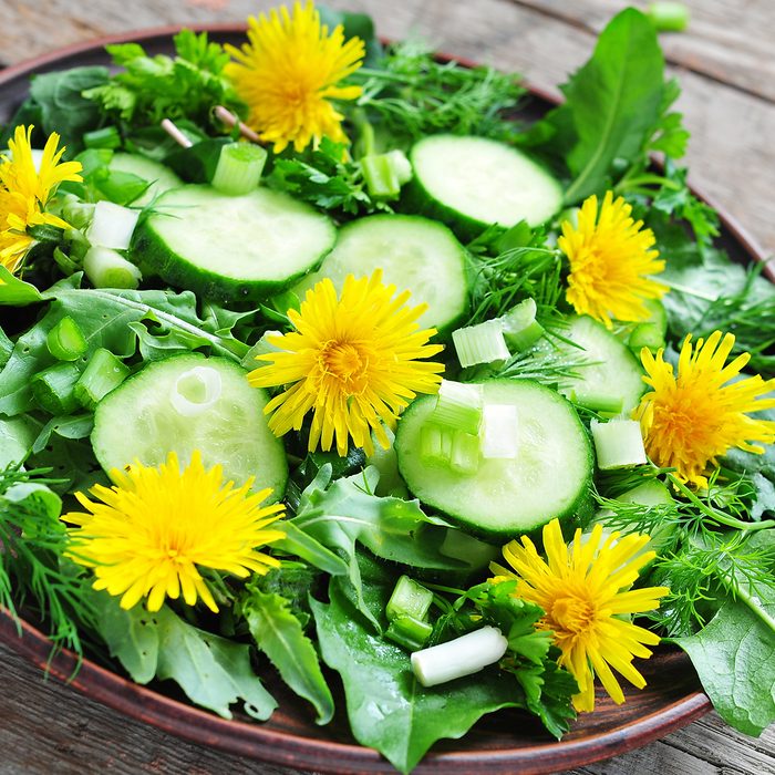 Fresh salad with cucumber, rucola, green onion and dandelion's flowers