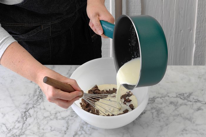 A person adding heavy whipping cream to chocolate chips in order to make homemade chocolate ganache