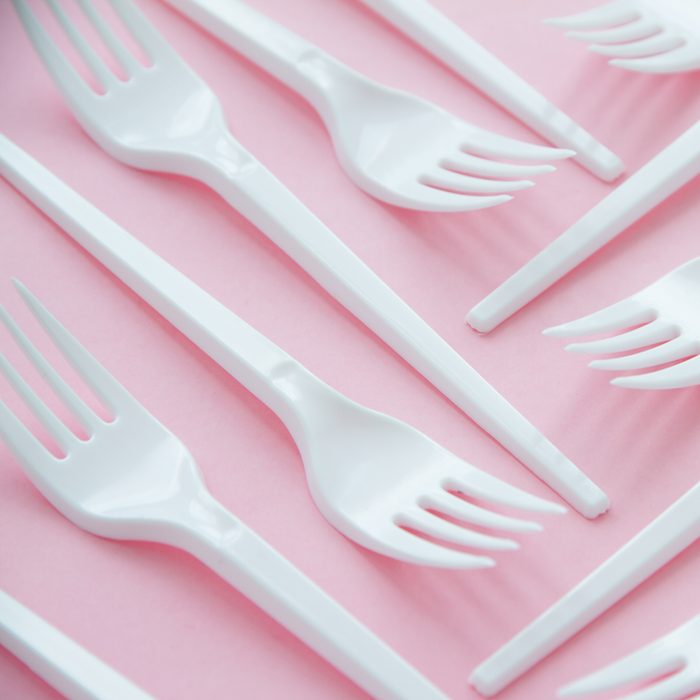 Minimalistic clean photo of white plastic disposable forks laying on table.