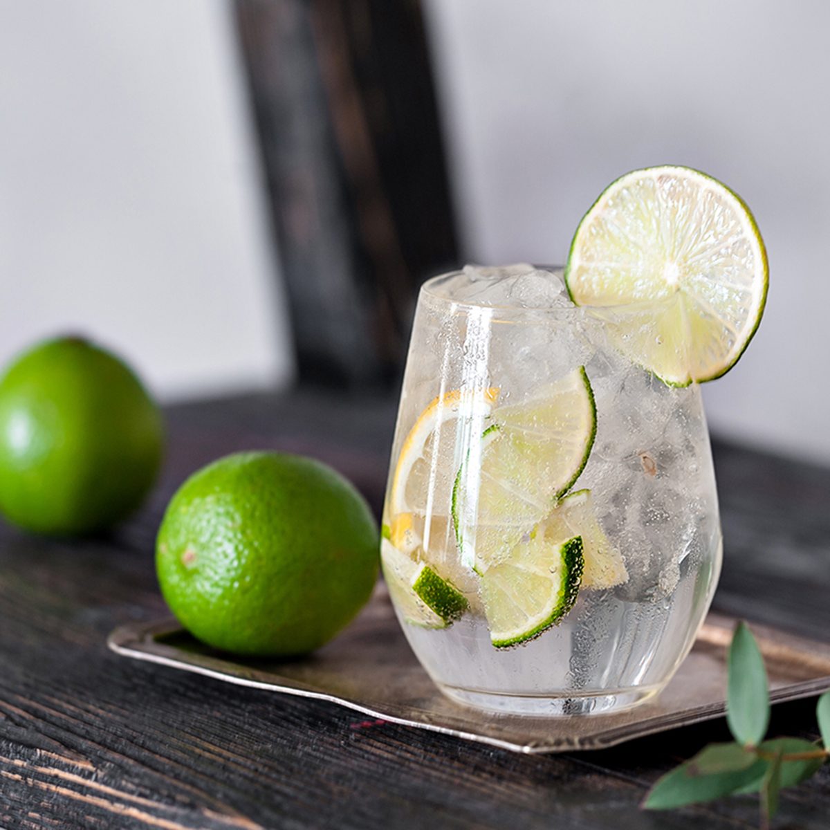 Cold cocktail with lime, lemon, tonic, vodka and ice on vintage background