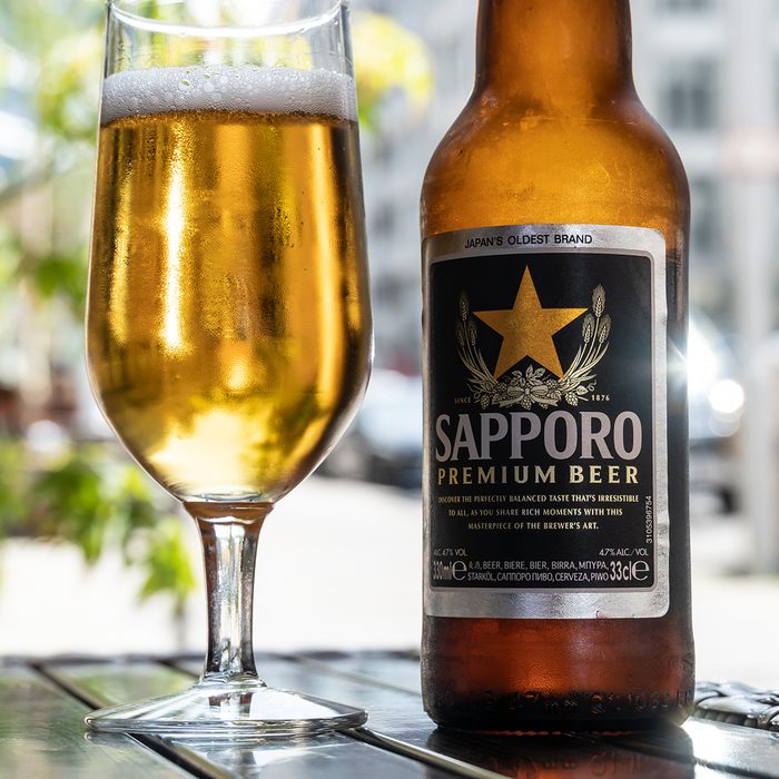 A glass full with beer next to a bottle of Sapporo Premium Beer on the table