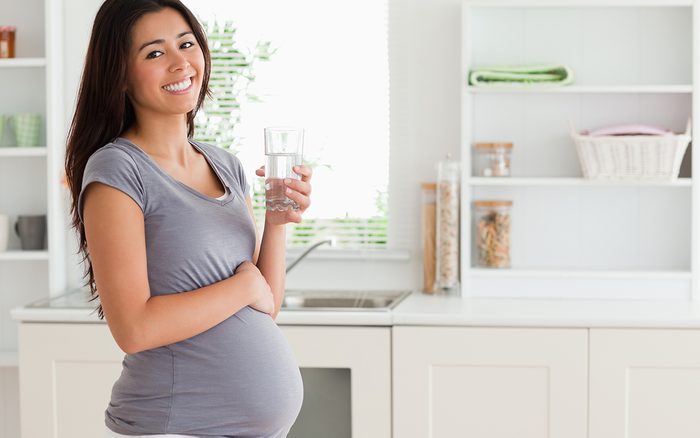 pregnant woman holding a glass of water in the kitchen