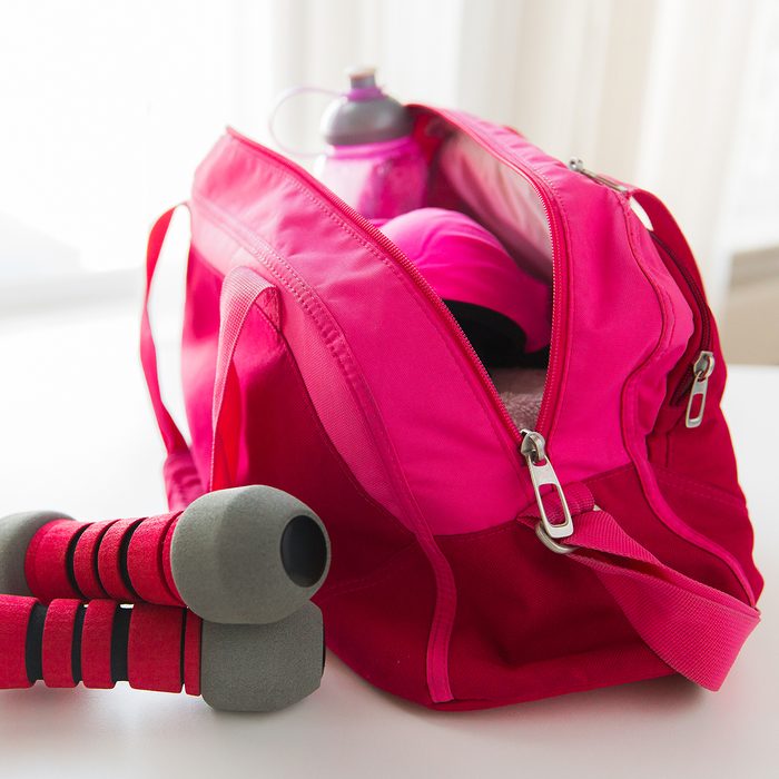 sport, fitness, healthy lifestyle and objects concept - close up of female sports stuff in bag and dumbbells