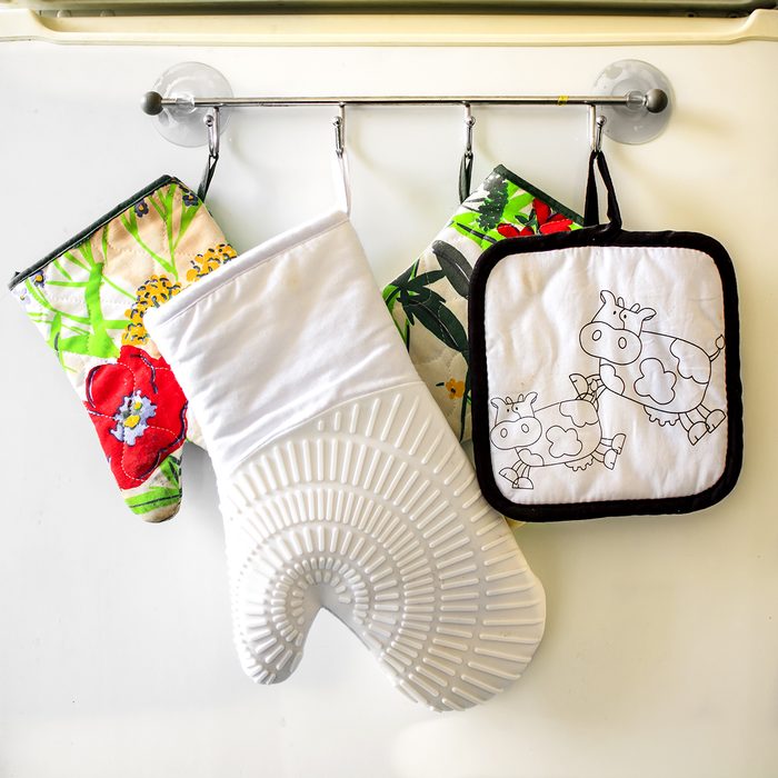 Oven gloves hanging in a row on the kitchen fridge