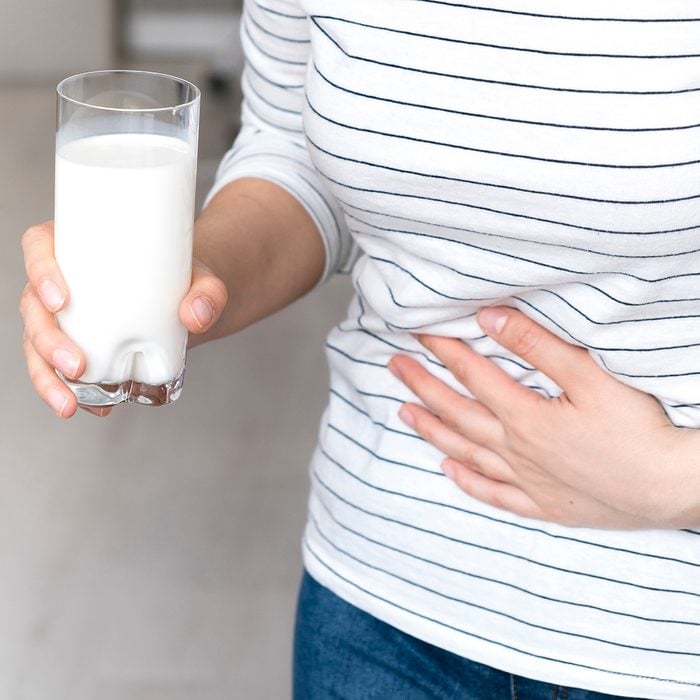 Lactose intolerance, health problem with dairy food products concept. Woman holding glass of milk having bad stomach ache.; Shutterstock ID 1027253146; Job (TFH, TOH, RD, BNB, CWM, CM): TOH