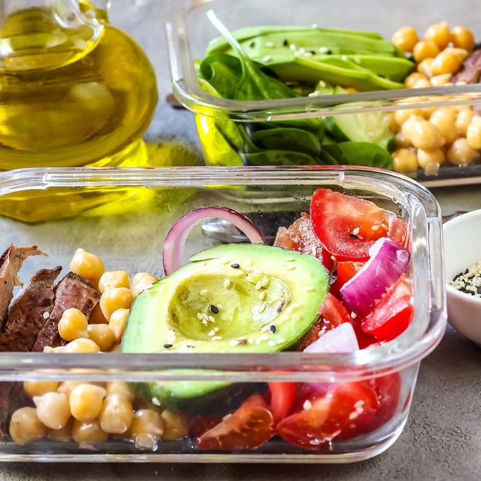 Healthy meal prep containers with chickpeas, goose meat , tomatoes, avocado, lemon and spinach. Top view; Shutterstock ID 1081277720