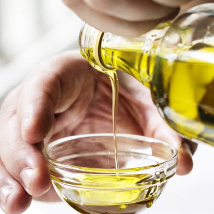 Closeup of hands pouring virgin olive oil