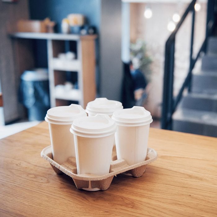 Take coffee to work for the entire office. High angle shot of a cardboard take out tray with four coffee cups with lids.
