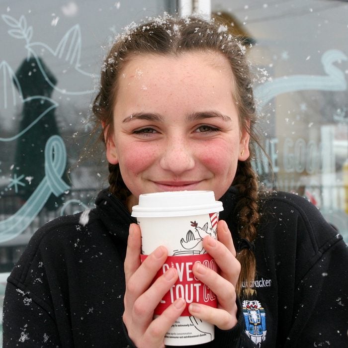 Young teenage girl enjoying a starbucks holiday drink outside in the snow