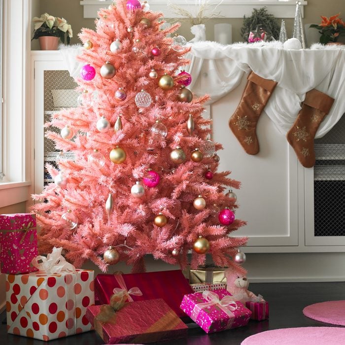 Pink Christmas Tree In Domestic Setting with Pink and Gold Christmas Balls, Pink Wrapped Presents and Christmas Decorations along the fireplace mantle behind the Christmas Tree