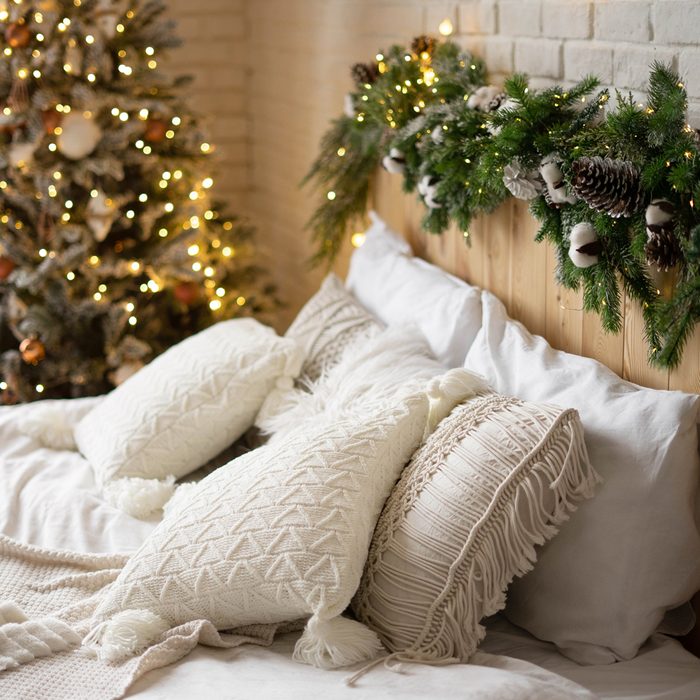 Decorated Christmas Bedroom With Christmas Tree and natural pine and pine cone garland wrapped around bed headboard