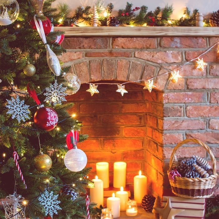 Decorated Living Room with Candles, Christmas Tree, Brick Fireplace and Assorted Decorations Along the Fireplace Mantle