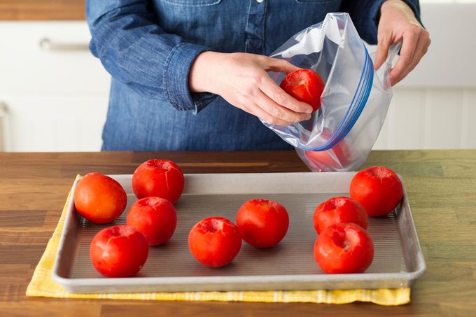 woman placing cored tomatoes into plastic ziplock bag