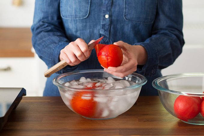 woman peeling tomatoes in ice bath