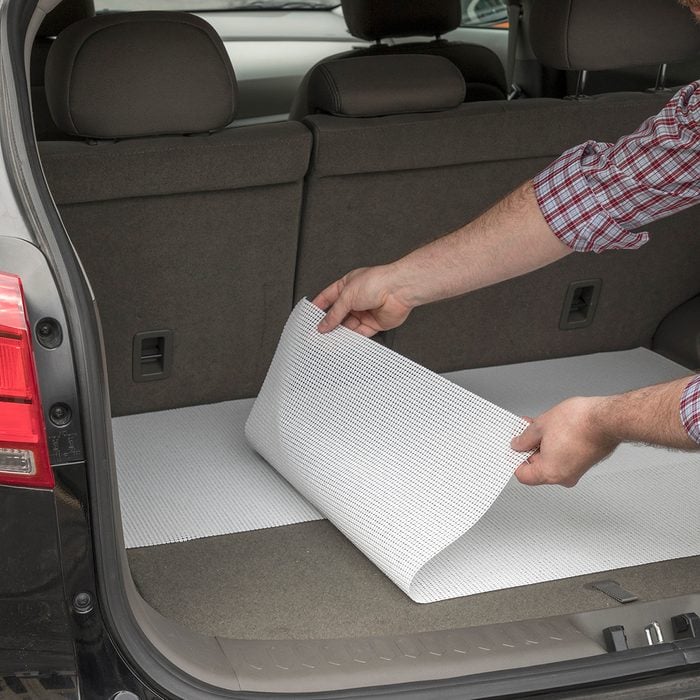 Man lining the trunk of a car with shelf liners