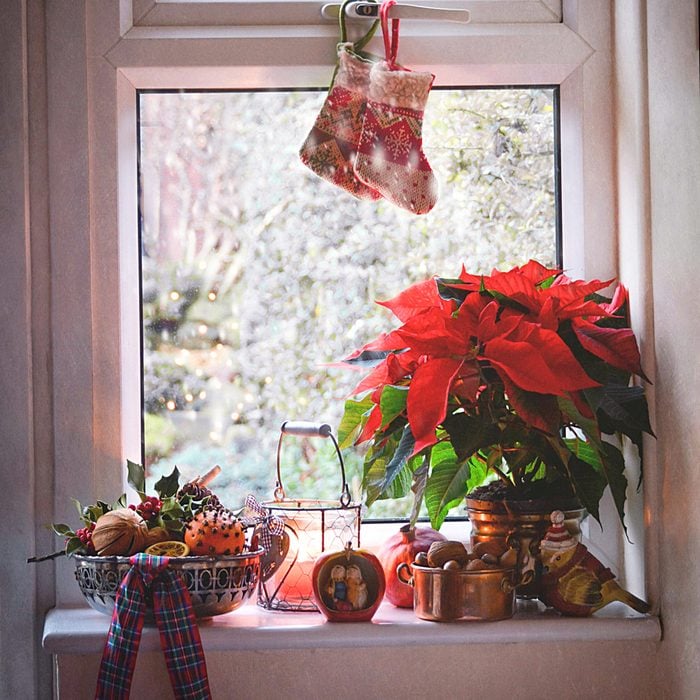 Decorated Window At Christmas with Potted Poinsettias, Ribbon, Stockings and Ornaments along the window edge