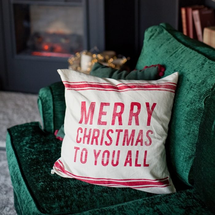 Dark Christmas Interior With Christmas Pillow, fireplace and emerald green sofa