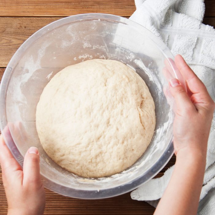 Woman Hands holding a bowl with wheat pizza or pie dough, shaped into ball on floured wooden background.; Shutterstock ID 1185130477; Job (TFH, TOH, RD, BNB, CWM, CM): TOH