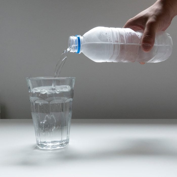 Картинка, наливающая пластиковую бутылку с водой в стеклянный стакан