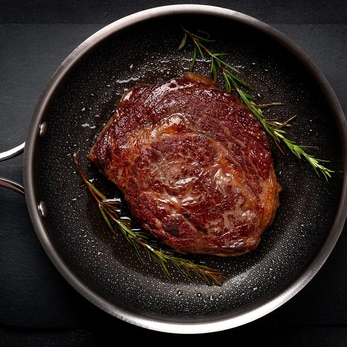 Grilled premium rib eye beef steak in the pan, cooking steak in the kitchen on a dark background