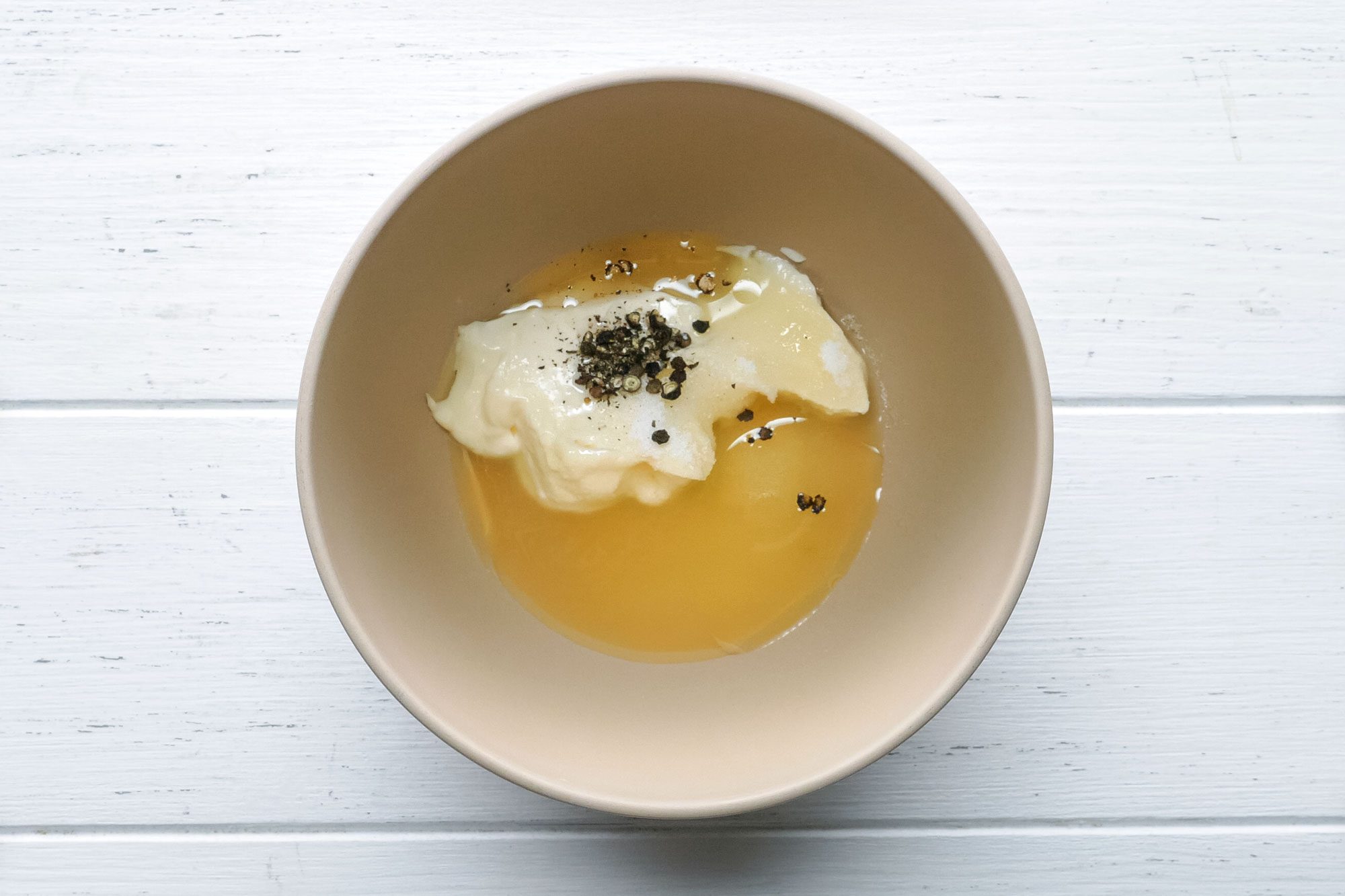 mayo, lemon juice, sugar, olive oil, salt and pepper in a small bowl on painted wooden surface
