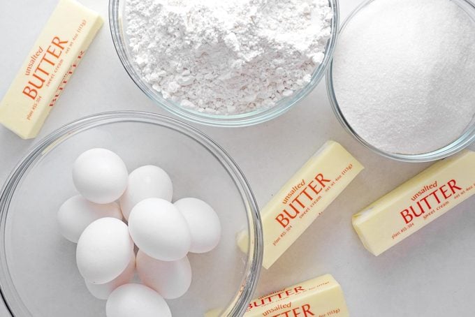 ingredients for a pound cake in glass bowls on a white countertop