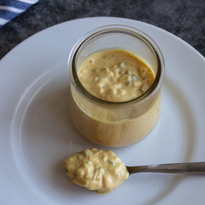 Glass jar with Big Mac Sauce on a white plate with a spoonful of sauce as well.