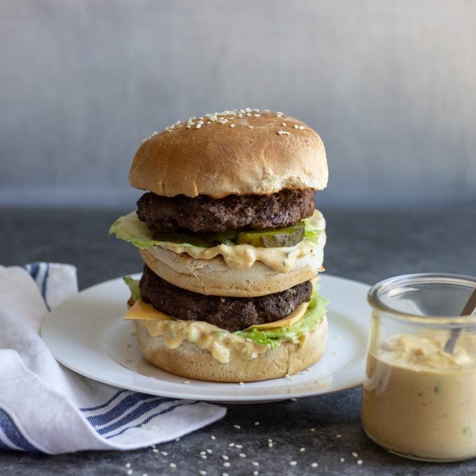 Stacked double cheeseburger with lettuce on a white plate.