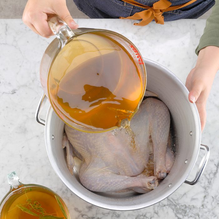 pouring brine over raw turkey